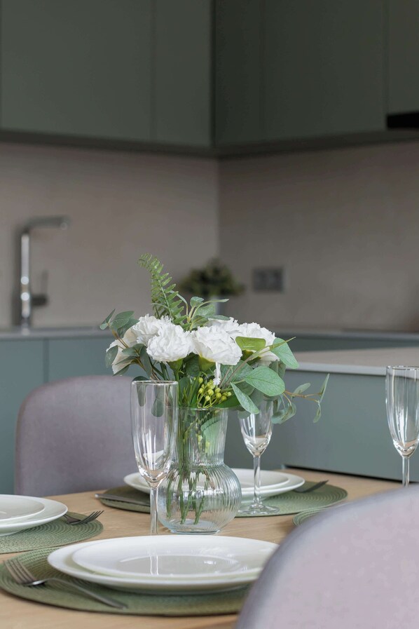 A dining table set with plates, cutlery, and a vase of flowers.