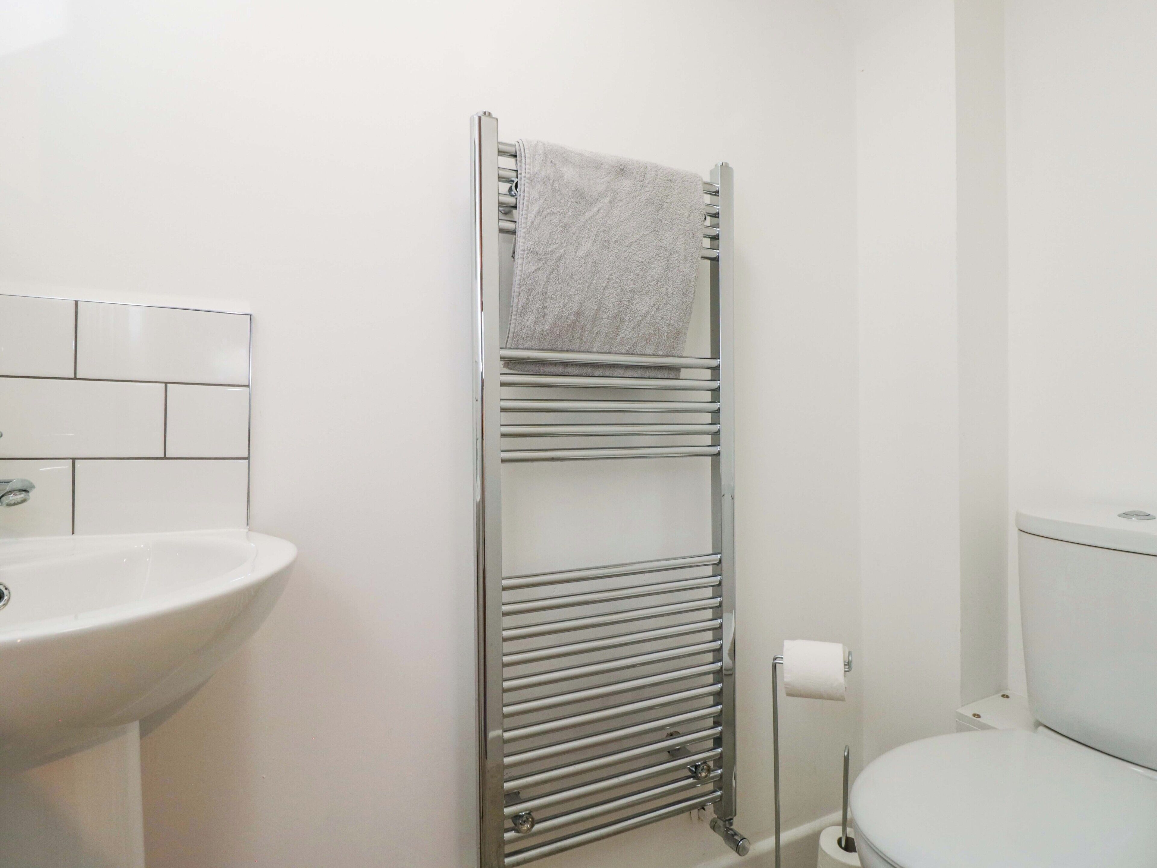 Ein Badezimmer mit einem weißen Waschbecken, einer Toilette und einem Handtuchhalter mit einem gefalteten Handtuch.