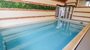 A swimming pool with a tiled edge, surrounded by brick walls and a green plant wall. - Barn Cottage (Frome)