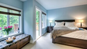 A bedroom with a bed, bedside tables, a window with a view, and a bench with a vase and glasses.