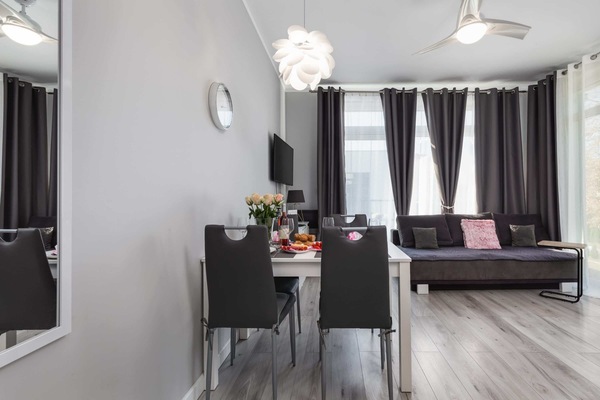 A stylish dining and living area featuring a dining table set for four, a cozy sofa, and large windows for natural light.