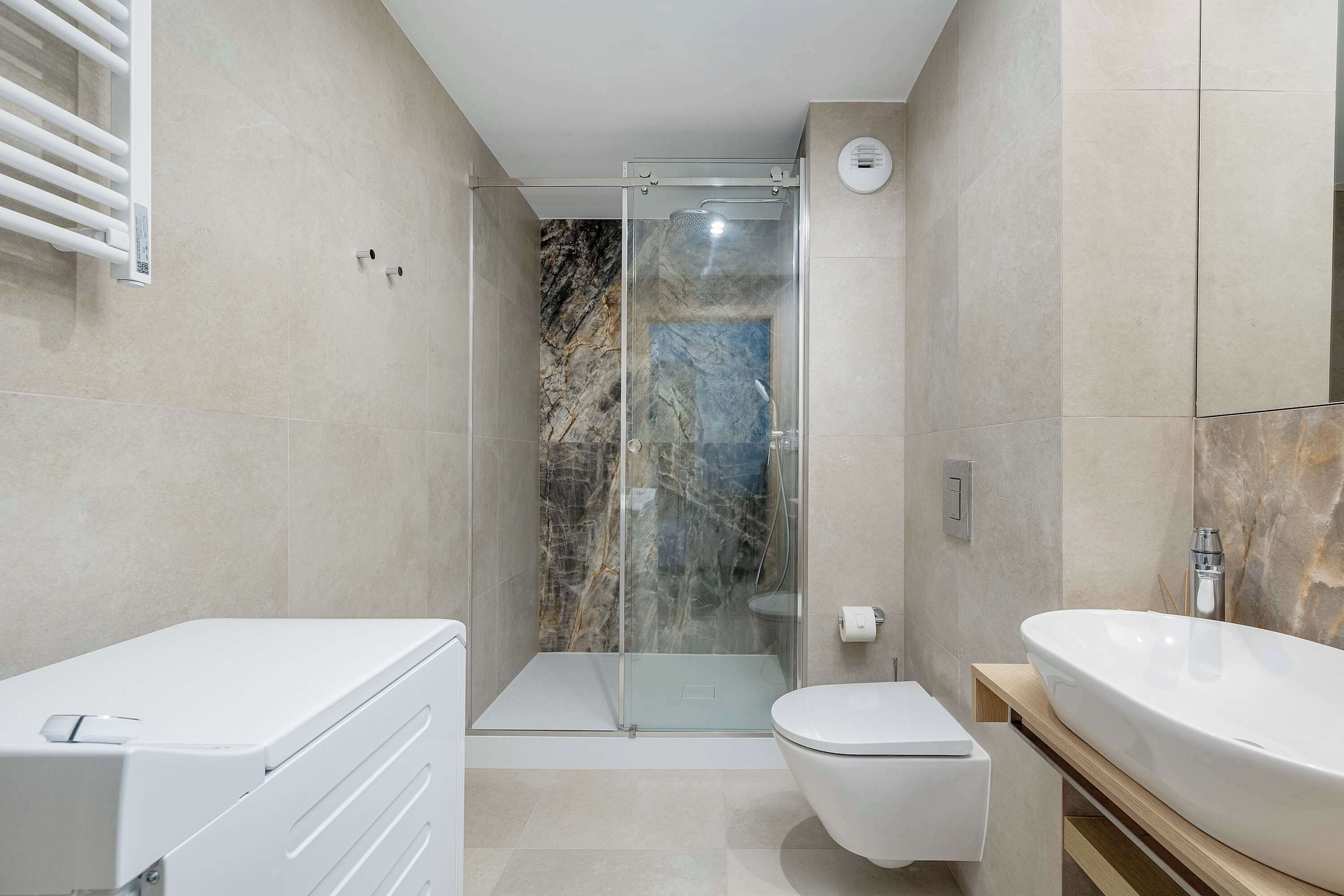 Une salle de bain moderne avec une douche à parois de verre, des toilettes blanches et un grand lavabo.