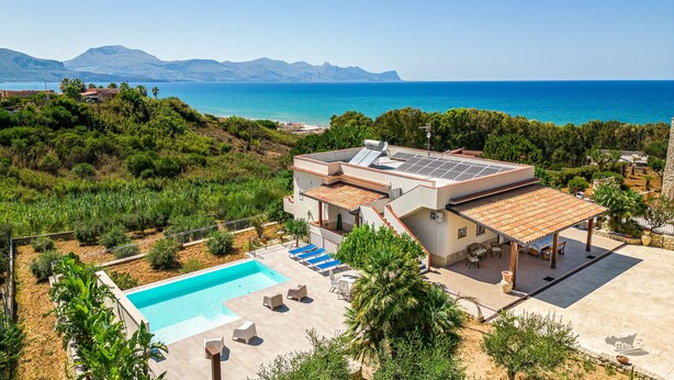 A modern villa with a swimming pool, outdoor seating, and a view of the sea and mountains. - Villa DellAcqua: Infinity Pool with Sea View (Alcamo)