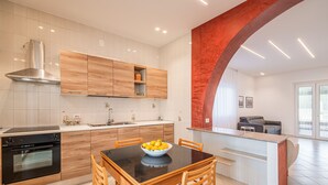 A modern kitchen with wooden cabinets, a black countertop, and a bowl of fruit on the table. - Villa DellAcqua: Infinity Pool with Sea View (Alcamo)