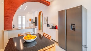 A modern kitchen with a large stainless steel refrigerator, a bowl of lemons on the counter, and a wooden dining table. - Villa DellAcqua: Infinity Pool with Sea View (Alcamo)
