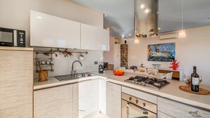 A modern kitchen with white cabinetry, a built-in microwave, a gas stove, and a sink. - Villa DellAlbero: Privacy, Relax and Unique Pool (Alcamo)
