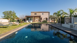 A swimming pool with lounge chairs and a building with a stone facade. - Villa DellAlbero: Privacy, Relax and Unique Pool (Alcamo)