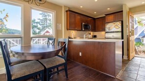 Una cocina con armarios de madera, una isla central, una mesa de comedor con sillas y vistas al exterior.