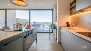 A modern kitchen with a large island, a dining area with a view, and a built-in oven. - Villa Brezza: Infinity Pool with Sea View (Partinico)