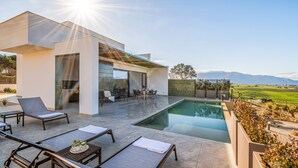 A modern outdoor pool area with lounge chairs, a table with drinks, and a view of the countryside. - Villa Brezza: Infinity Pool with Sea View (Partinico)