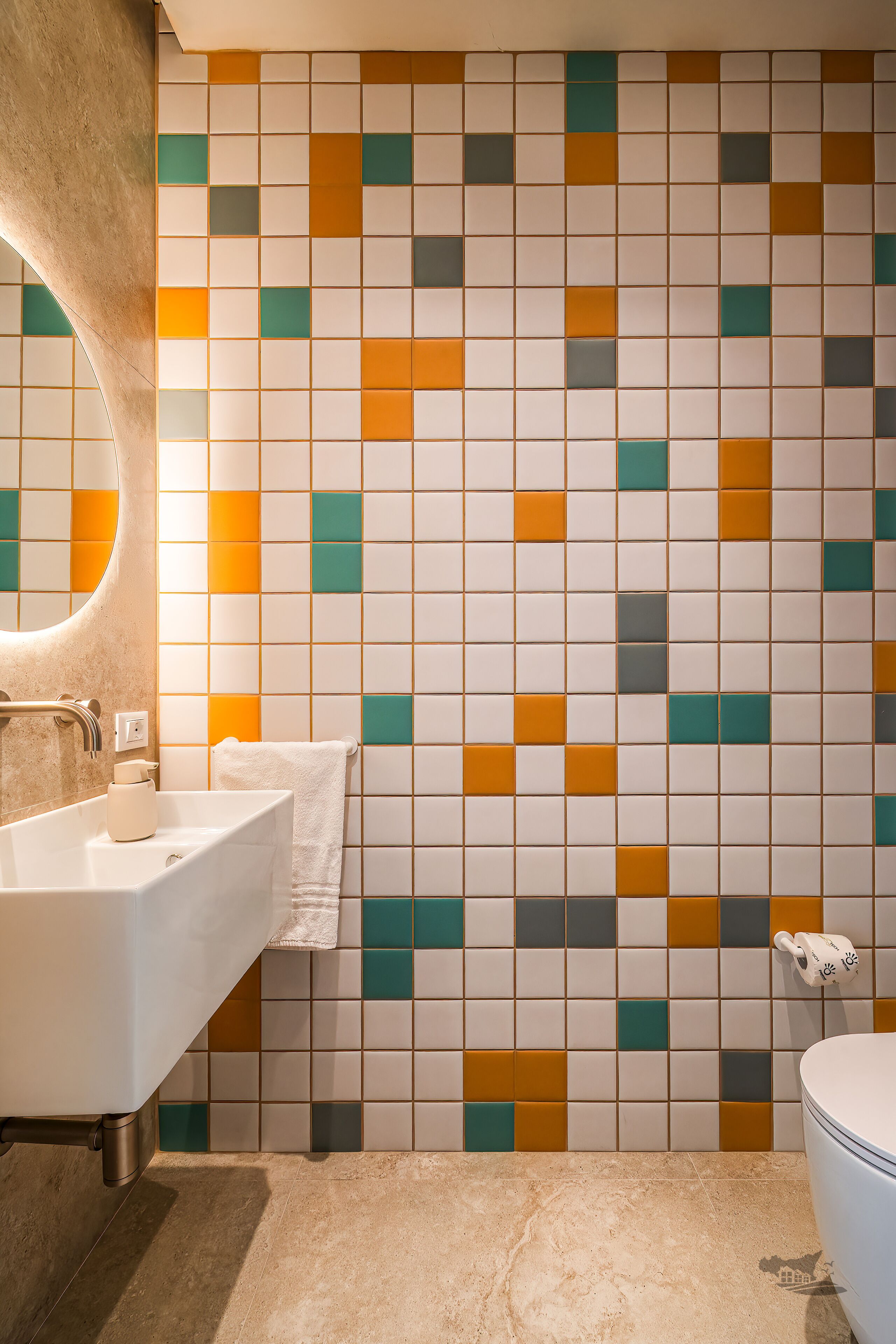 A bathroom with a tiled wall, a sink, a mirror, and a toilet.