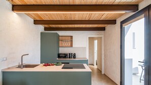 A modern kitchen with a central island, built-in appliances, and a wooden ceiling. - Villa Castello: Pool with Sea and Castle Views (Partinico)