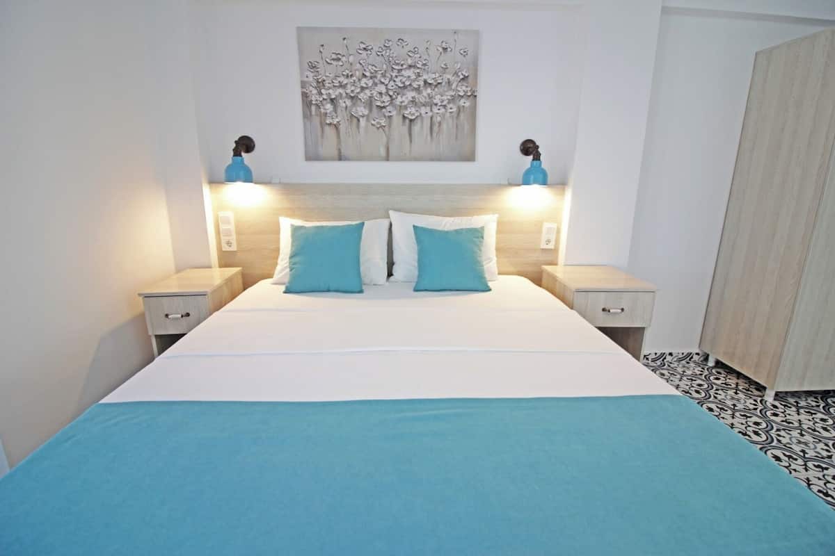 Una camera da letto con un letto, due comodini, un'opera d'arte appesa al muro e un pavimento decorato.