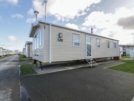 Yhden kerroksen omakotitalu, jossa on etukuisti, pieni siihen kiinteästi rakennettu autotalli ja satelliittiantenni.