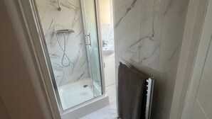 A modern bathroom with a glass-enclosed shower, marble walls, and a towel rack. - Sunny Gardens London House Retreat (London)