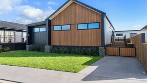 A modern two-story house with a sloped roof, large windows, and a well-maintained lawn.