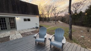 A deck with two Adirondack chairs and a house in the background.