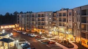 A multi-story hotel with a parking lot and outdoor seating area. - Landing Weston Lakeside Apartments (Cary)