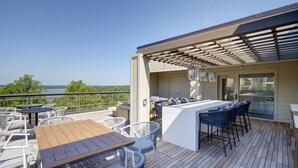 A deck with outdoor seating, a bar area, and a view of the lake. - Landing Weston Lakeside Apartments (Cary)