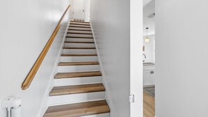 A staircase with wooden steps and a wooden handrail, leading to a white door at the top.