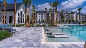 Un resort con piscina, palmeras y un edificio de varias ventanas.