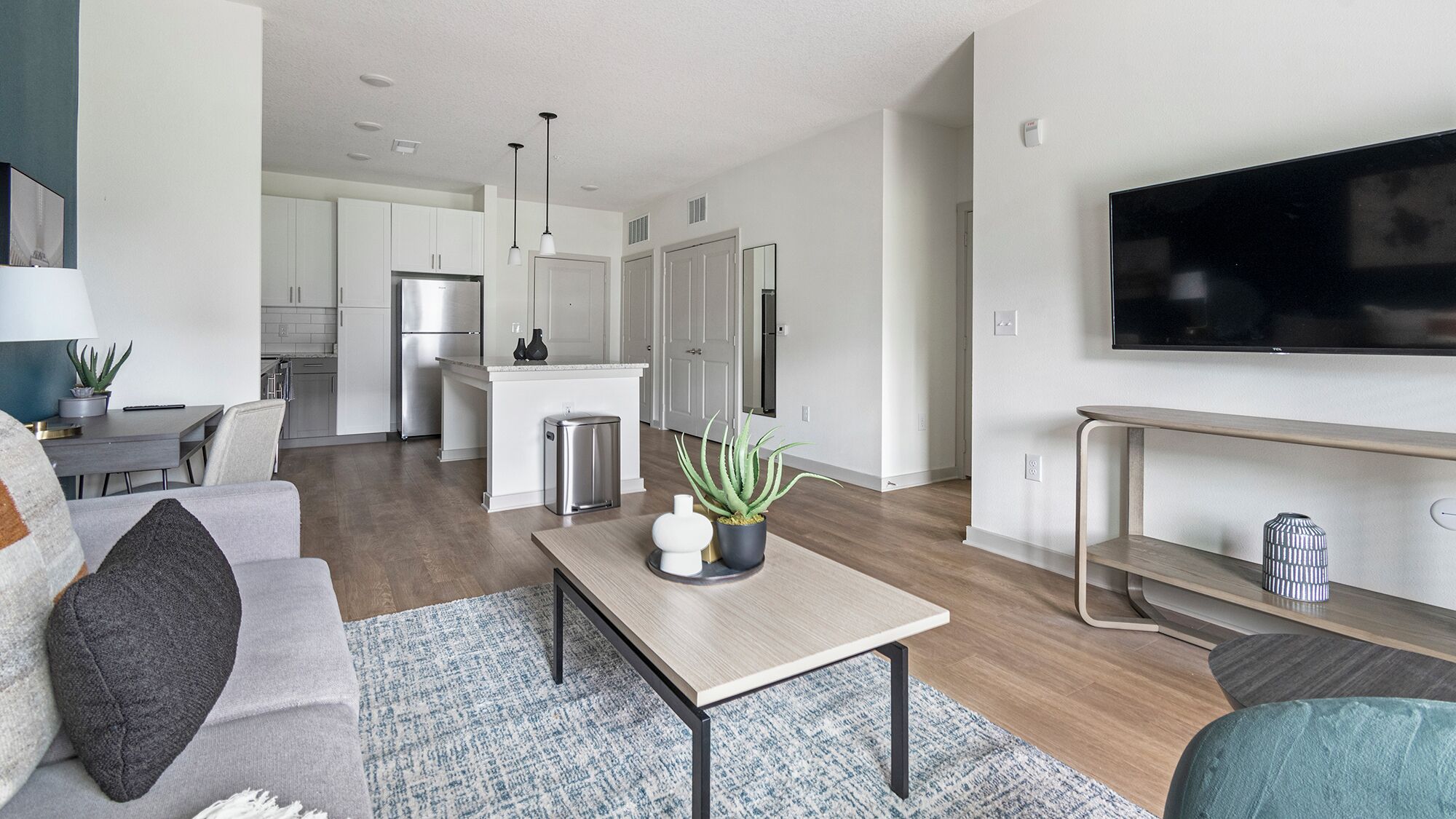 A modern living room with a sofa, coffee table, and a TV mounted on the wall.
