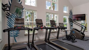 Un gimnasio con cintas de correr, elípticas y bicicletas estáticas.