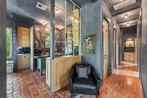 A modern kitchen with a marble backsplash, wooden cabinets, and a built-in microwave. - Ebb and Glow Retreat by Ryson Vacation Rentals (Galveston)