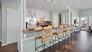 Une cuisine moderne avec un coin bar, des meubles blancs et un grand vase.
