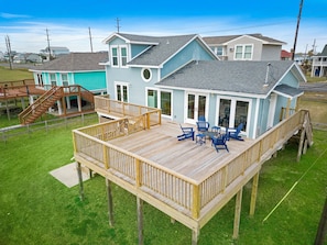 A two-story house with a deck, outdoor seating, and a staircase. - Our Infinity Pool by Ryson Vacation Rentals (Galveston)