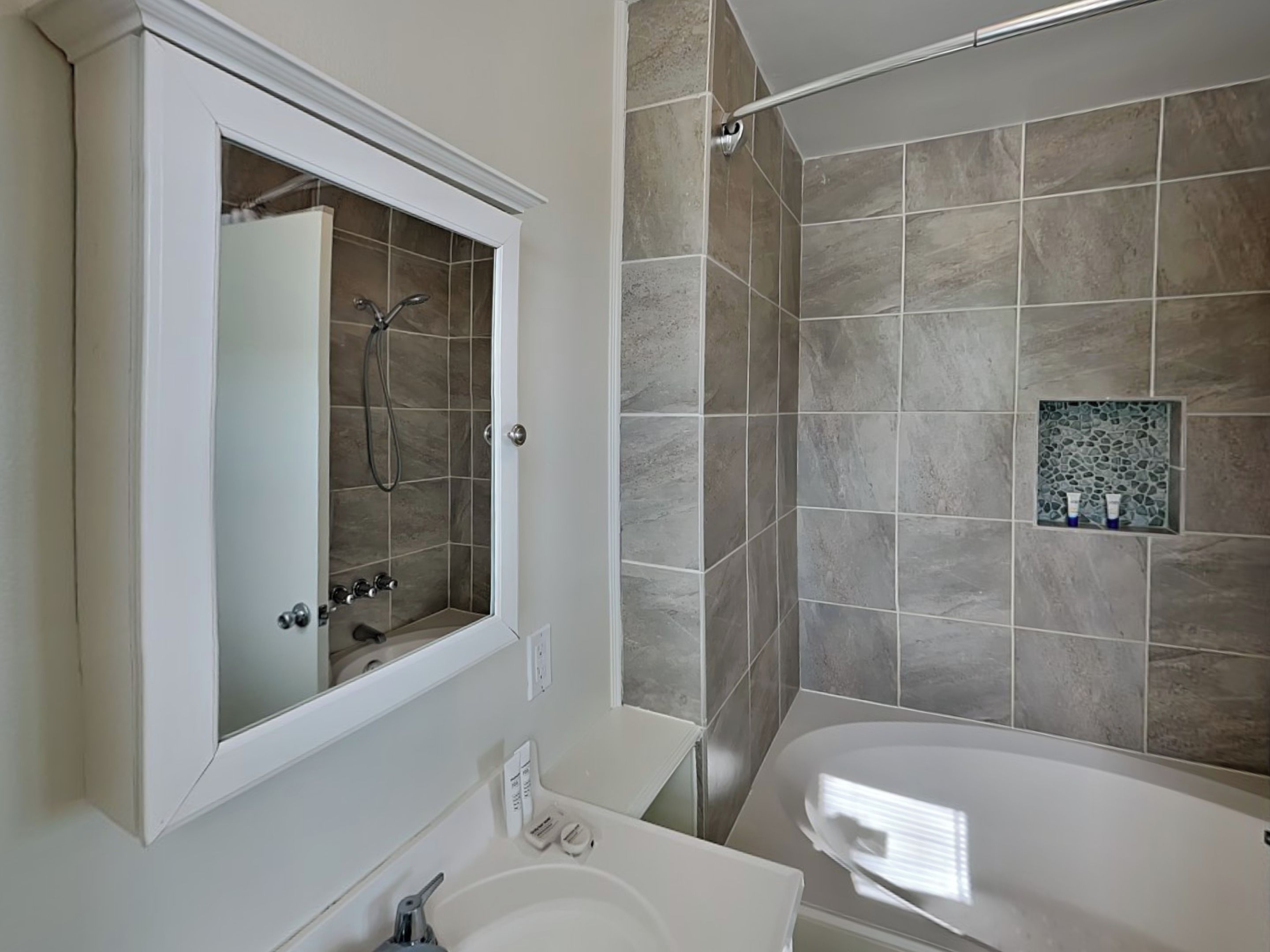 Une salle de bain moderne équipée d’une baignoire, d’une douche et d’un meuble-lavabo avec un miroir.