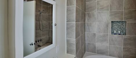 Une salle de bain moderne équipée d’une baignoire, d’une douche et d’un meuble-lavabo avec un miroir.