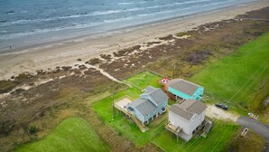 Luchtbeeld van een kustbezit met een strand, huizen en een gazon.