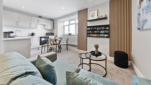 Un espace de vie moderne comprenant une cuisine, un coin repas et un coin salon confortable avec un canapé et une petite table basse.