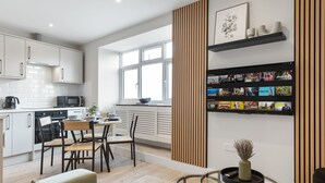 Une cuisine moderne avec des meubles blancs, un coin repas avec une table et des chaises, et un salon avec un canapé et une table basse.