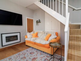 Una sala de estar con un sofá, una mesita redonda, una chimenea y una escalera.