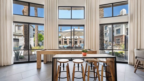 A modern kitchen with a central island, bar stools, and large windows offering views of the surrounding area. - Boulevard Stays Chic 1BR Near Stadium Pool Access, Gym & Free Parking (Glendale)