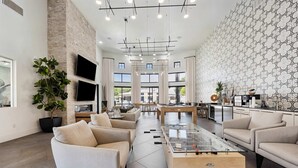 A spacious living area with a modern design, featuring a large sofa, a coffee table, and a kitchen area with a dining table. - Boulevard Stays Chic 1BR Near Stadium Pool Access, Gym & Free Parking (Glendale)