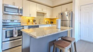 A modern kitchen with stainless steel appliances, a granite countertop, and a built-in island with stools.