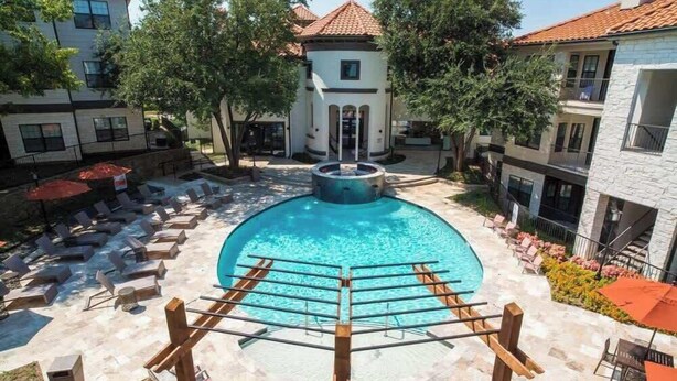 A swimming pool with lounge chairs and a wooden pergola in the foreground.