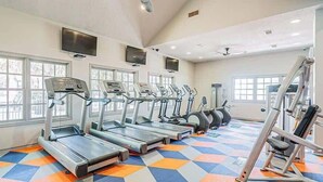 A gym with multiple treadmills, exercise bikes, and a colorful floor pattern. - Boulevard Stays Calm 1BR King Retreat Poolside Bliss Gym & Parking (Arlington)