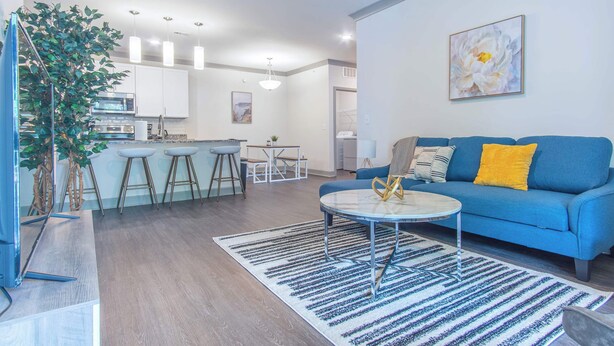 A modern living room with a blue sofa, a round coffee table, and a large plant.