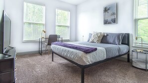 A bedroom with a bed, a desk, and a chair.