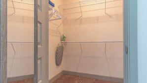 A walk-in closet with metal shelving units, a green iron, and a patterned iron board.