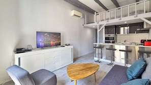 Una cocina moderna con una isla grande, taburetes de bar y un televisor de pantalla plana.