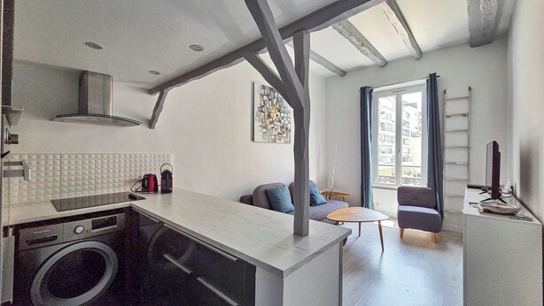 Een moderne keuken met een wasmachine, een eethoek met een tafel en stoelen, en een zithoek met een bank.