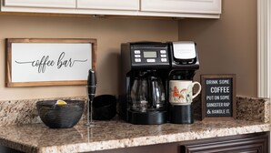 Un comptoir de cuisine avec une machine à café, une tasse, un bol et un panneau sur lequel on peut lire : « BUVEZ UN CAFÉ, ÉCOUTEZ DU RAP GANGSTA ET OCCUPEZ-VOUS DE VOS AFFAIRES. »
