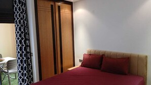 A bedroom with a bed, a desk, and a wardrobe.