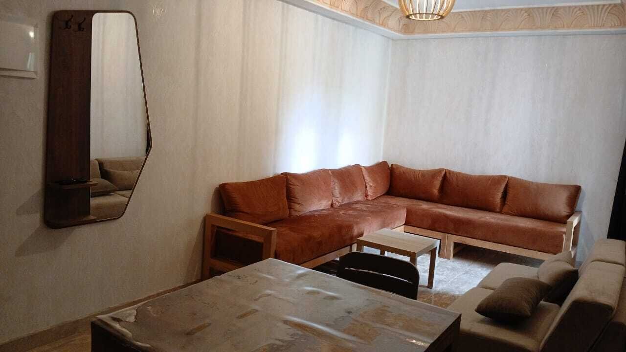 Un salon avec un canapé en cuir marron, une petite table et un miroir au mur.