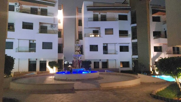 A multi-story building with a central courtyard featuring a fountain and a swimming pool.